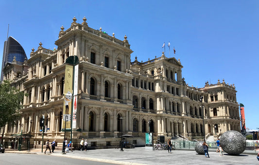 The heavy sandstone facade and classical colonnades of the historic Treasury Building in the Brisbane CBD.