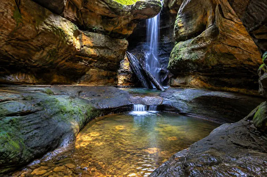 Small waterfall feeding a deep, shaded plunge pool inside the slot canyon at Centennial Glen, Blackheath