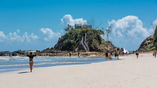 Longboarders in the lineup at The Pass, Byron Bay, with Cape Byron behind