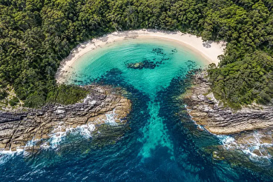 Clear, sheltered water in the horseshoe-shaped cove of Honeymoon Bay, framed by bushland on the Beecroft Peninsula