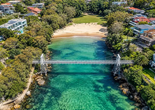 The timber suspension bridge spanning Parsley Bay above calm green harbour water in Vaucluse