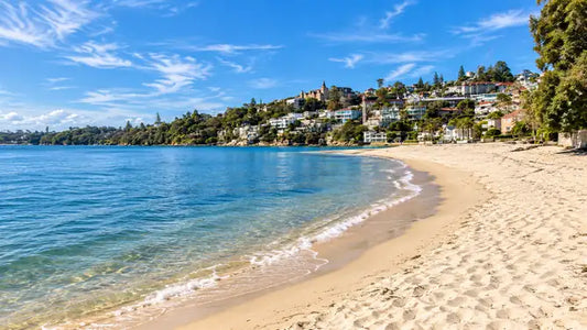 Wide sweep of sand at Rose Bay Beach with calm Sydney Harbour water and boats moored offshore
