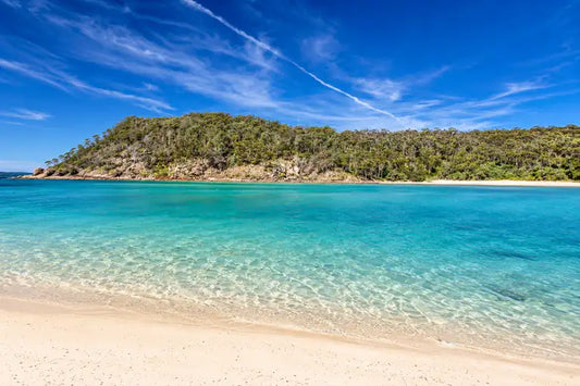 Turquoise water and white sandbanks at Pambula River Mouth with the forested headland of Beowa National Park