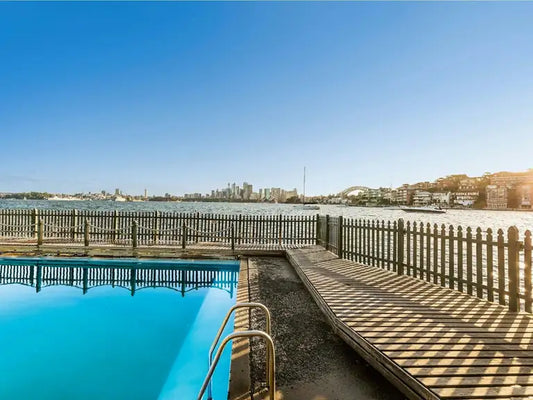 MacCallum Pool's timber deck and harbour pool at Cremorne Point with the Sydney Harbour Bridge and city skyline across the water